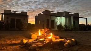 A modern house with a fire pit in the foreground and a sunset in the background. - Vista Sierra Laguna (El Pescadero)