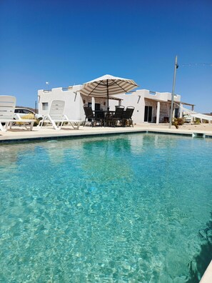 A clear pool with a white building and lounge chairs in the background. - Vista Sierra Laguna (El Pescadero)