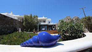 Een modern huis met een stenen muur en een blauw beeldhouwwerk op de voorgrond.