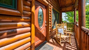 A wooden cabin with a porch, a door with a decorative glass panel, and a chair. - Stunning 5BD Cabin! HOT TUB +Close to Town +VIEWS! (Sevierville)