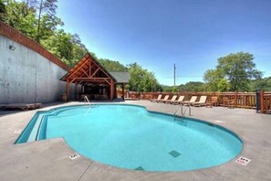 Una piscina con sillas de descanso y una estructura de madera.