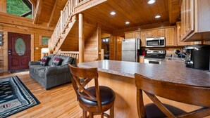 A wooden cabin interior with a kitchen, dining area, and a staircase. - Stunning 5BD Cabin! HOT TUB +Close to Town +VIEWS! (Sevierville)