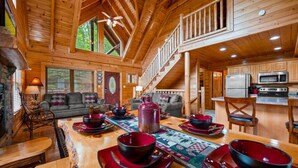 A wooden cabin interior with a dining area, kitchen, and living room. - Stunning 5BD Cabin! HOT TUB +Close to Town +VIEWS! (Sevierville)