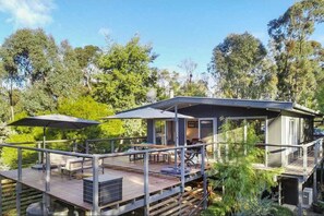Uma casa moderna com um deck, móveis de exterior e uma antena parabólica.