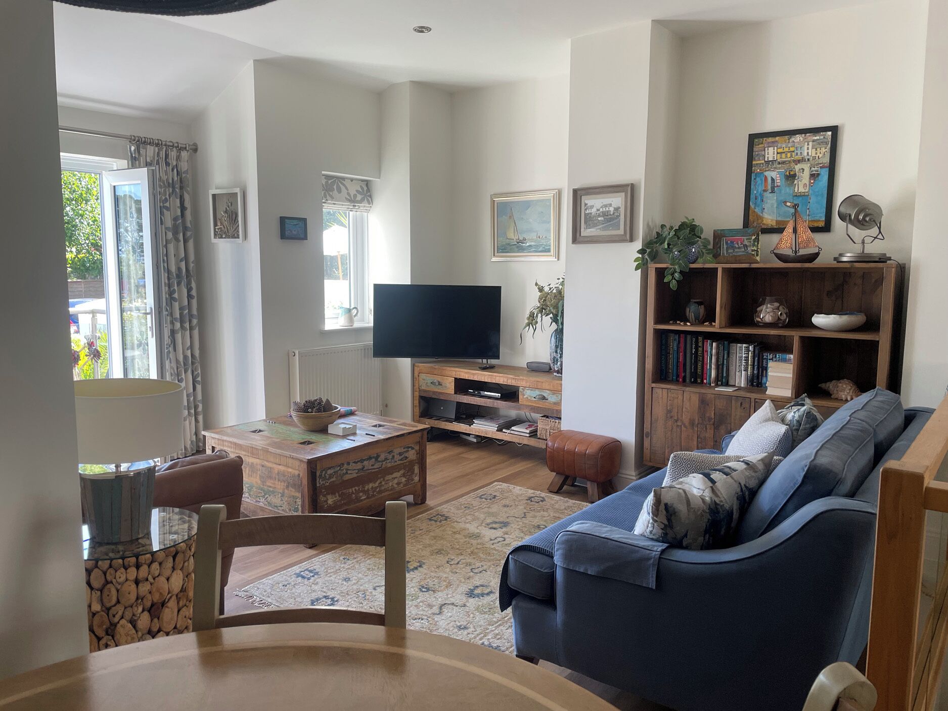 A living room with a TV, bookshelf, sofa, and a dining area with a table and chairs.
