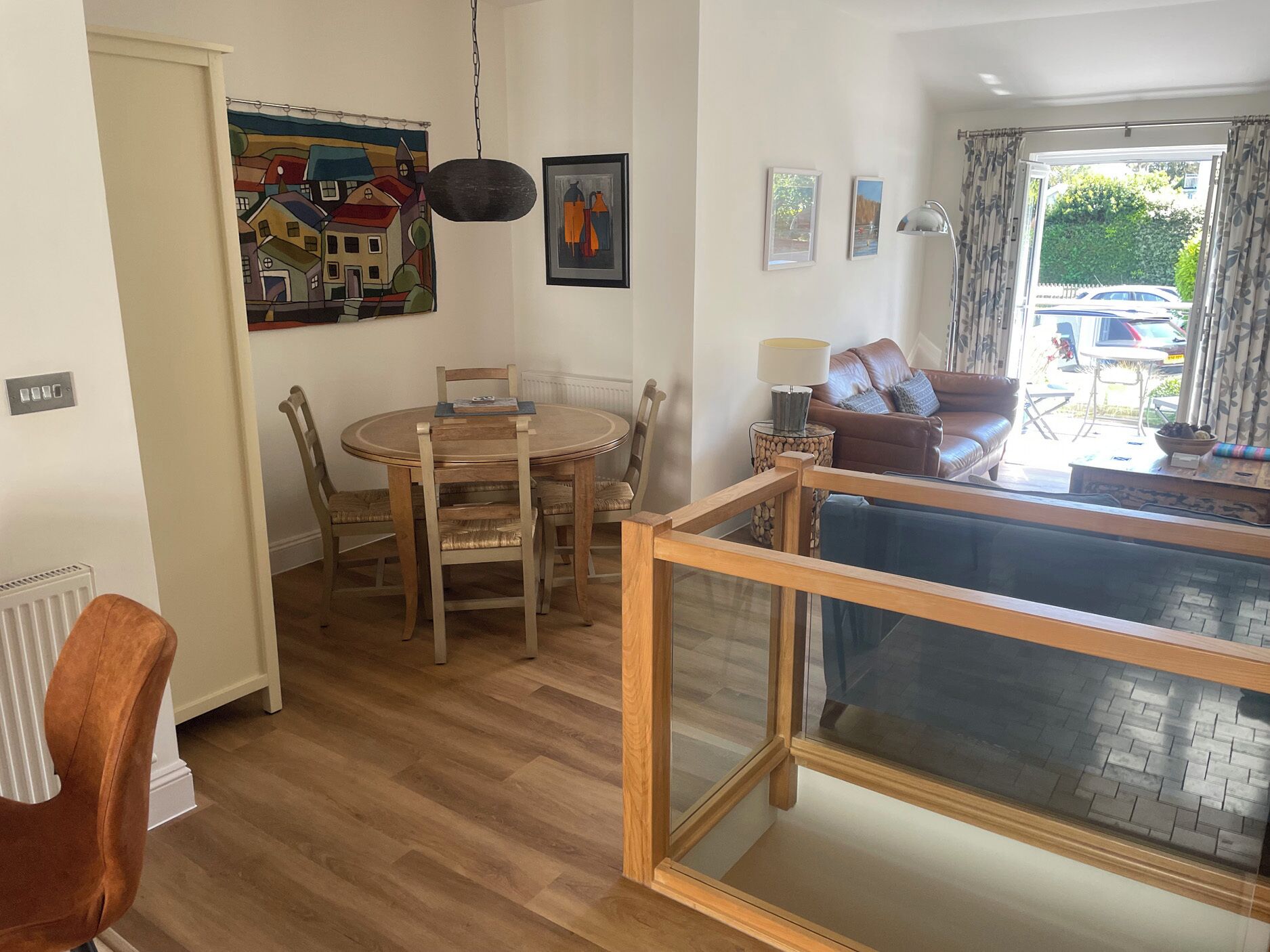 Una sala de estar con una mesa de comedor, sillas, un sofá, un televisor y una ventana con cortinas.
