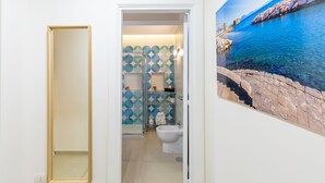 Een badkamer met douche, toilet en een decoratieve wand met geometrische patronen.