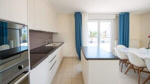 A modern kitchen with a dining area, white cabinets, and a view through the window. - Beautiful 3 bedroom apartment 20 min from Paris

 (Vigneux-sur-Seine)