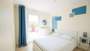 A bedroom with a large bed, a bedside table with a lamp, a wall clock, and a window with curtains. - Beautiful 3 bedroom apartment 20 min from Paris

 (Vigneux-sur-Seine)