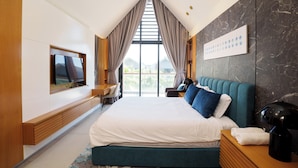 Une chambre d’hôtel moderne dotée d’un grand lit, d’un téléviseur à écran plat fixé au mur, d’un bureau avec une chaise et offrant une vue sur l’extérieur grâce à de grandes fenêtres.