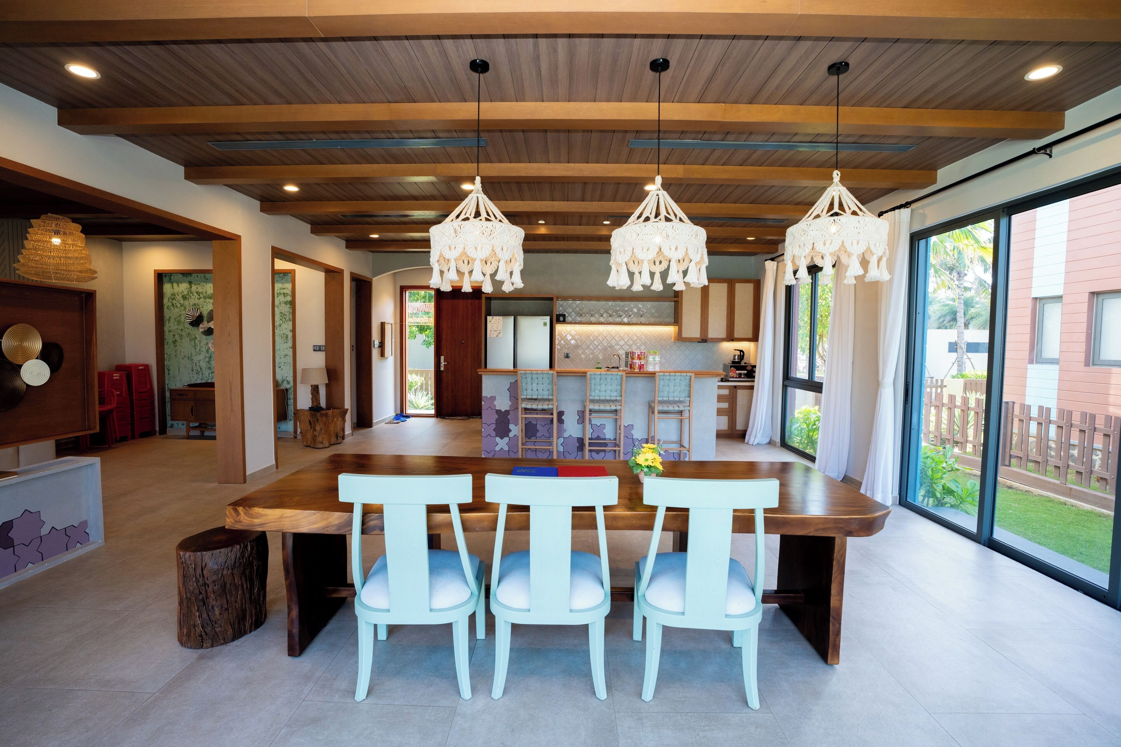 A spacious kitchen with a large island, wooden ceiling beams, and pendant lights.