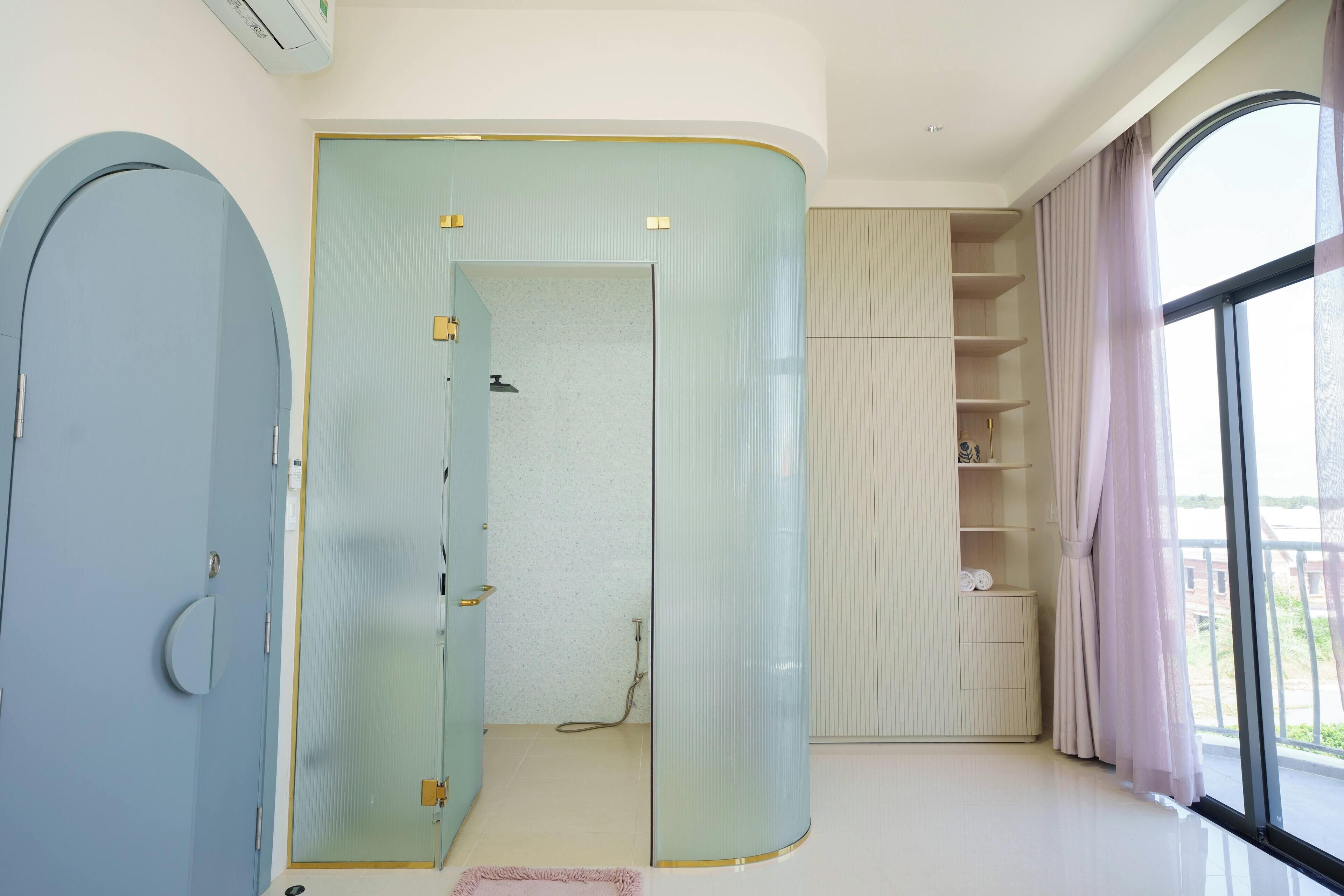 A room with a large wardrobe, a shower area, and a view through a window.