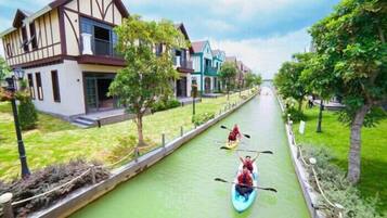 A canal with two kayaks, surrounded by houses and greenery.