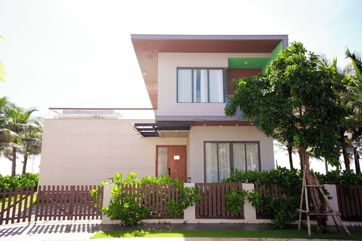 Une maison moderne à deux étages, dotée d’un toit plat, de grandes fenêtres et d’une clôture en bois.