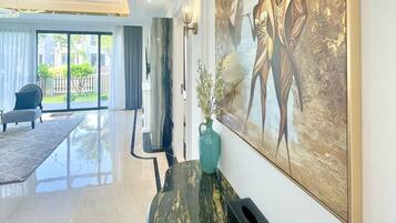 Un interior modern amb una recepció de marbre, un quadre abstracte gran i una vista de l'exterior a través d'una porta de vidre.