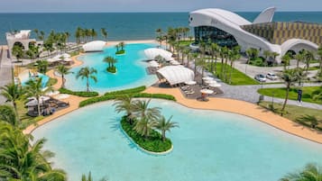 Et resort med en stor swimmingpool, palmer og en moderne bygning med et unikt design.