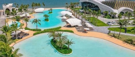Un resort con una piscina grande, palmeras y un edificio moderno de diseño único.