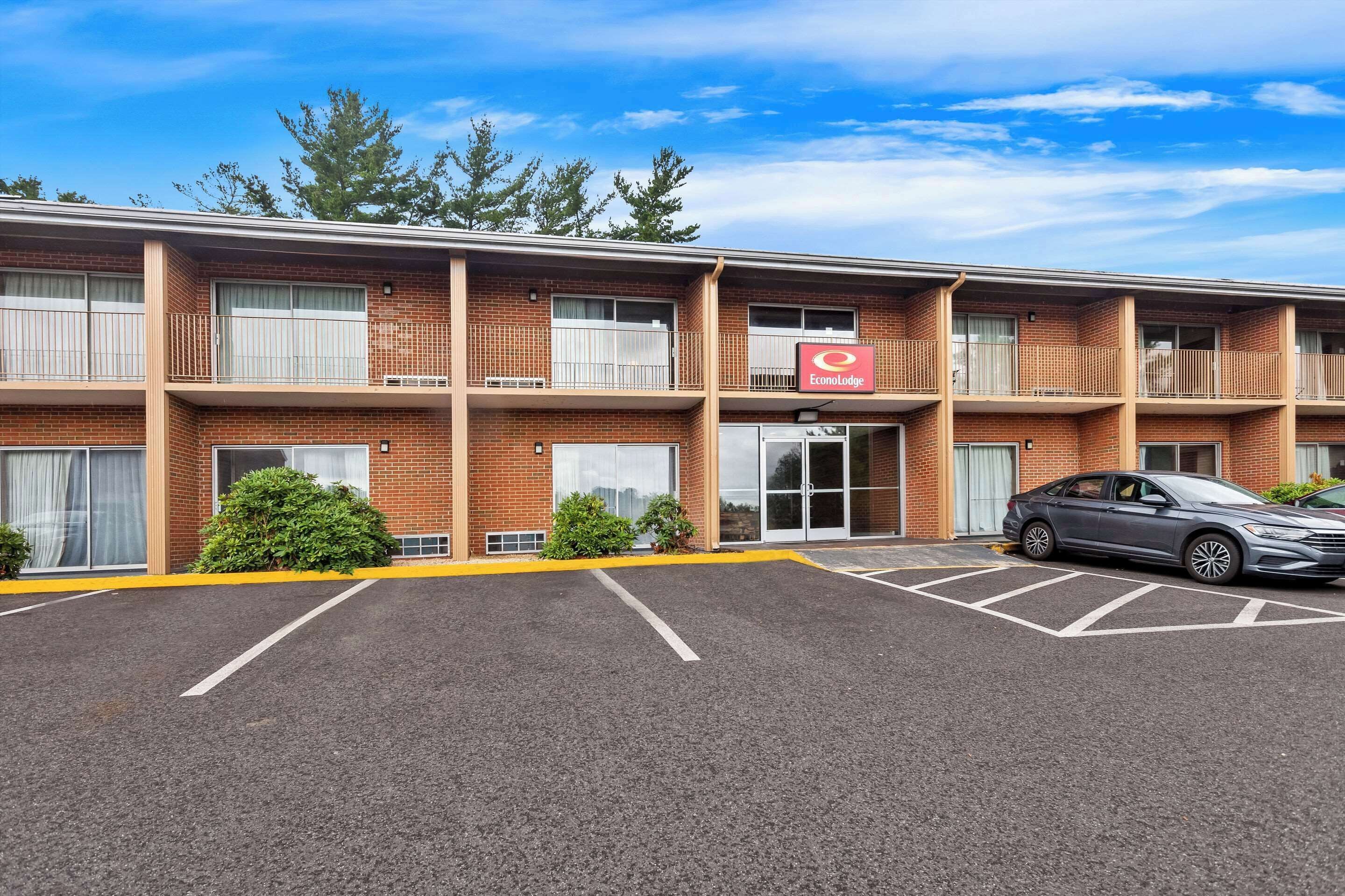 A multi-story brick building with a parking lot and a car parked in front.