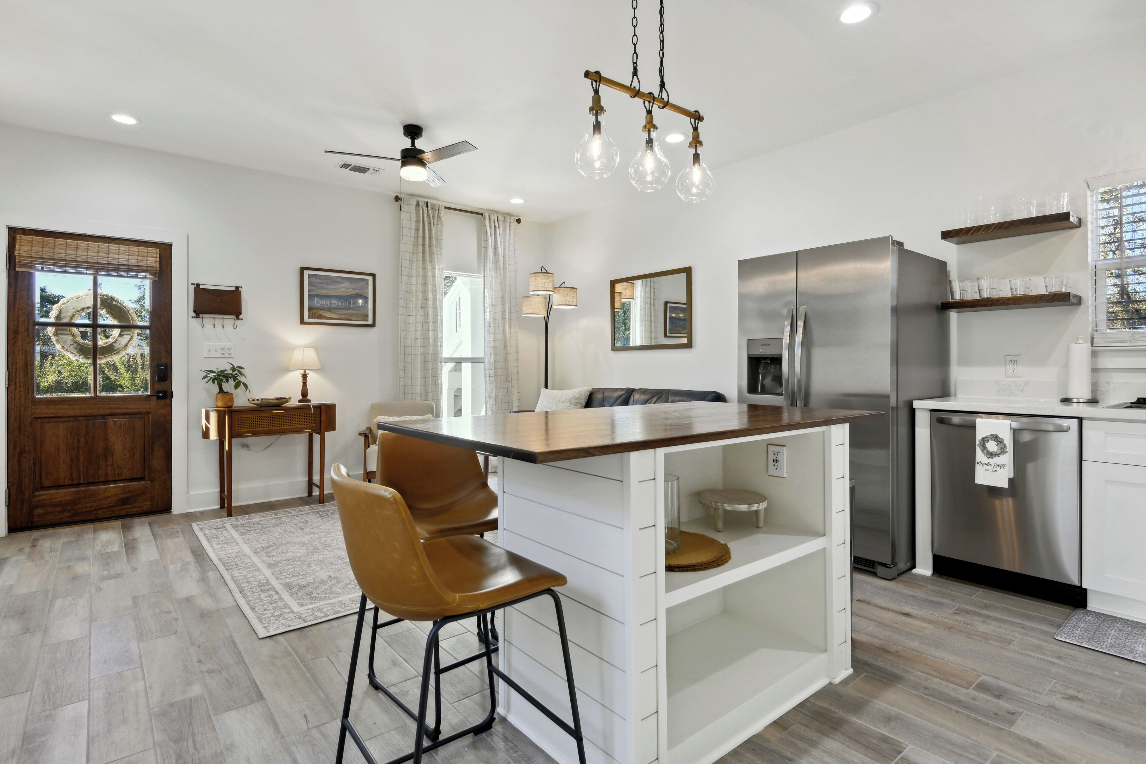 A modern kitchen with a central island, stainless steel appliances, and a ceiling fan.