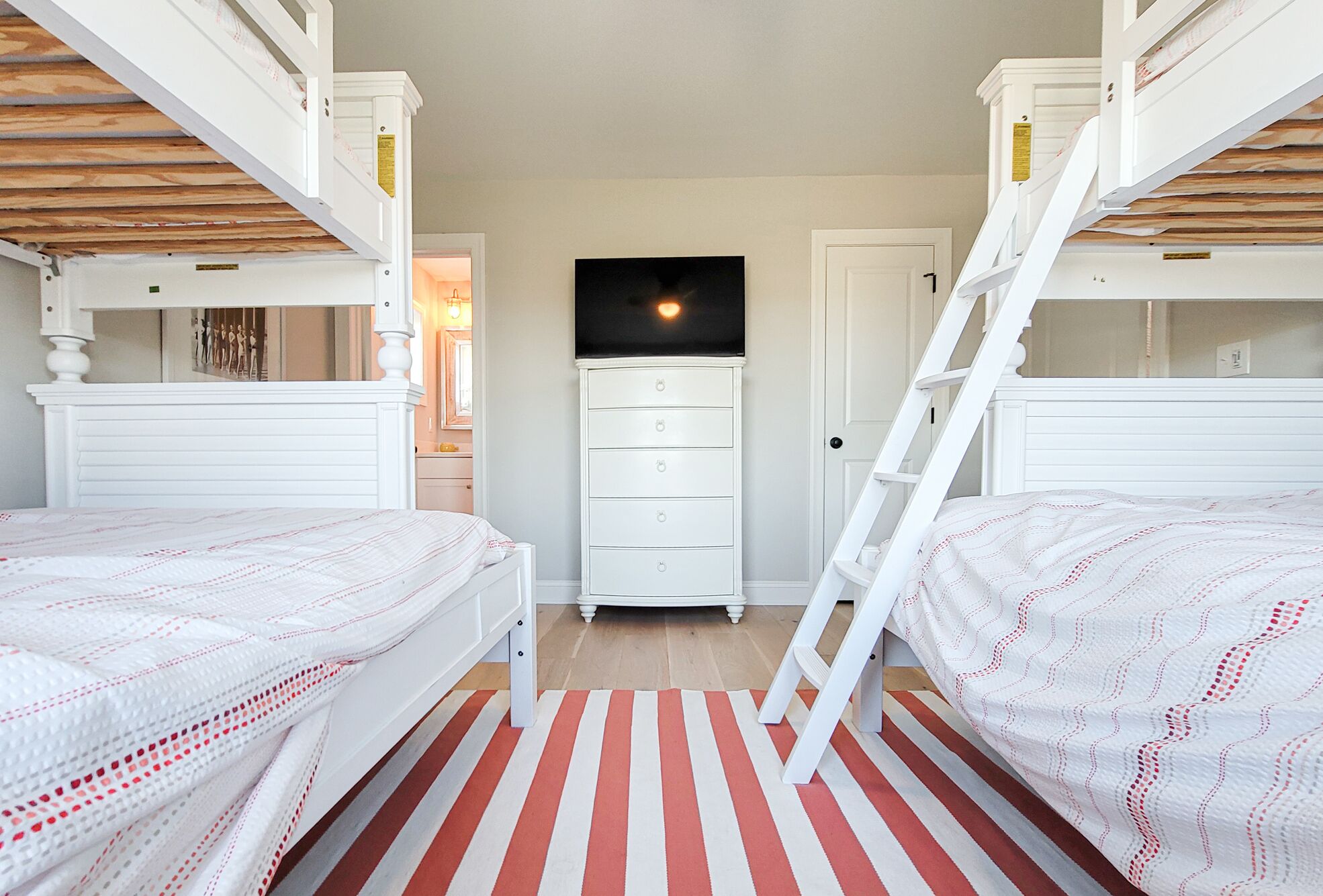Een slaapkamer met stapelbedden, een dressoir en een televisie.