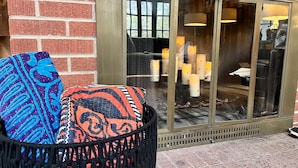 L’entrée d’un hôtel, avec une porte en verre, un mur de briques et une poubelle agrémentée de coussins aux couleurs vives.