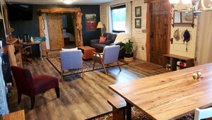 A cozy living room with a wooden dining table, comfortable seating, a fireplace, and a view of the outdoors. - Lake view, close to shopping, hiking, restaurants and boat launch. (Guntersville)