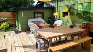 A wooden deck with a table and chairs, a small shed, and a wall with a leaf pattern. - Lake view, close to shopping, hiking, restaurants and boat launch. (Guntersville)