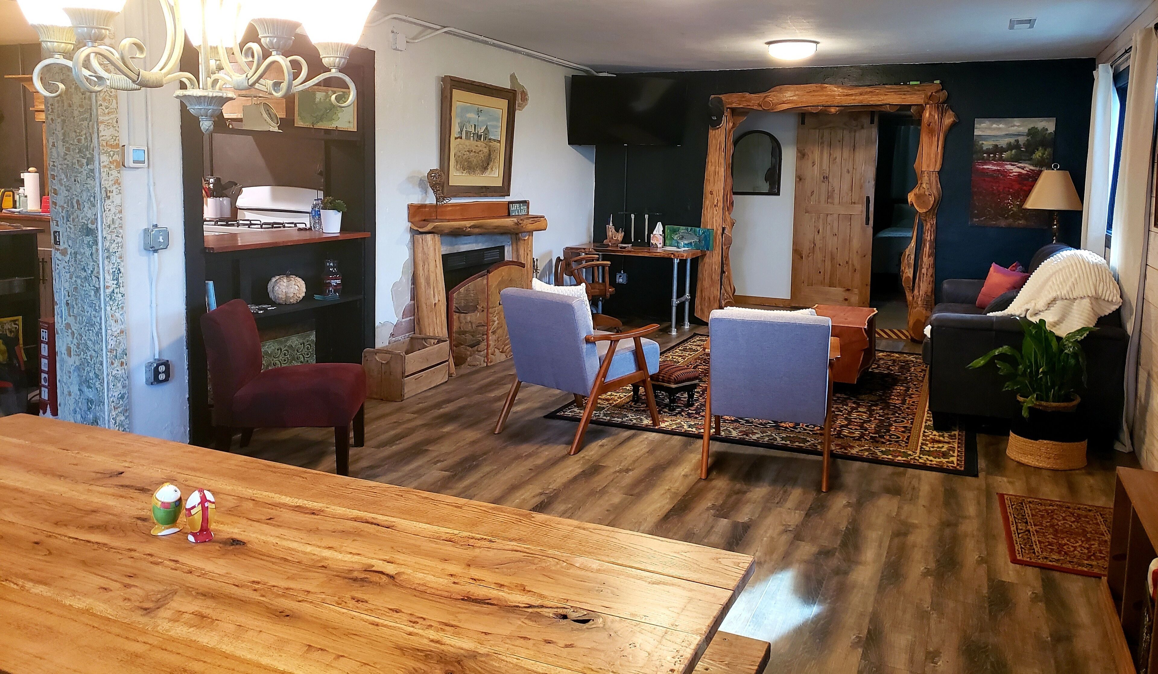 Una sala de estar acogedora con una mesa de comedor de madera, dos sillones, un sofá y una chimenea.