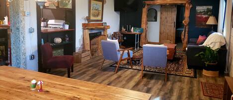 Una sala de estar acogedora con una mesa de comedor de madera, dos sillones, un sofá y una chimenea.