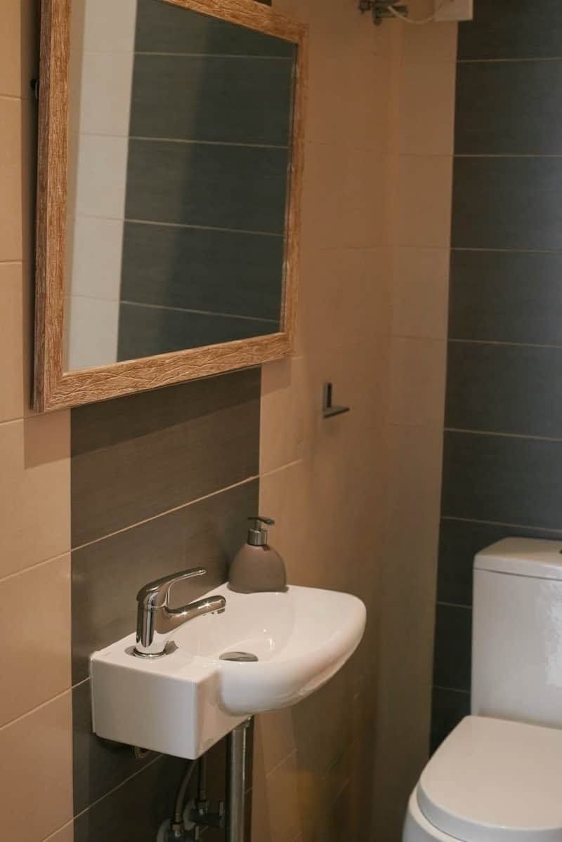 A bathroom with a white sink, a mirror, and a toilet.