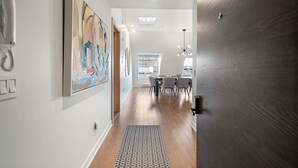 Un couloir avec un tapis à motifs, un tableau accroché au mur, un téléphone et un coin repas avec des chaises et une table.