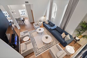 Uma sala de estar moderna com um sofá, duas mesinhas de centro redondas e uma televisão.