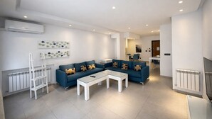 A modern living room with a blue sofa, white coffee table, and a white ladder. - Victor Hugo (La Marsa)