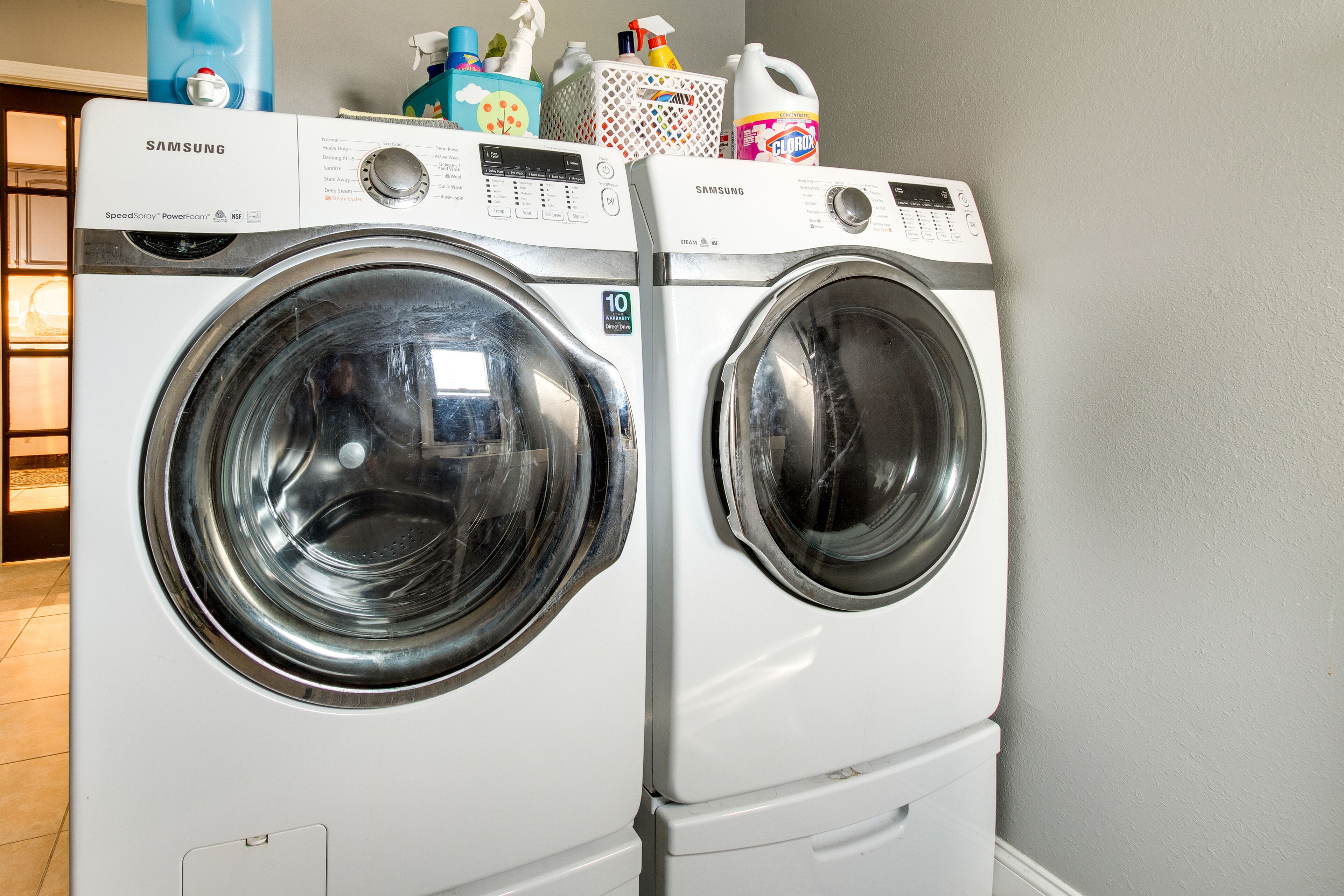 Un appareil combiné lave-linge et sèche-linge à chargement frontal de la marque Samsung, doté d’un panneau de commande et d’un autocollant de garantie.