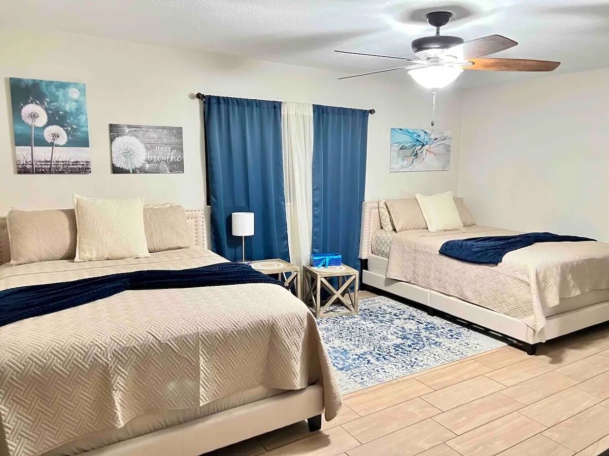 Une chambre d’hôtel avec deux lits, un ventilateur de plafond et des œuvres d’art accrochées aux murs.
