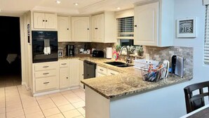 Una cucina moderna con mobili bianchi, piani di lavoro in granito e lavastoviglie integrata.