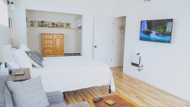 A bedroom with a bed, a wardrobe, a television, and a wall-mounted air conditioning unit.