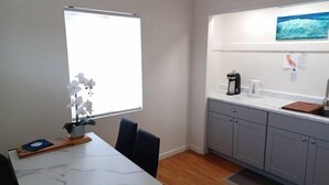 A modern kitchen with grey cabinets, a white countertop, and a coffee maker.
