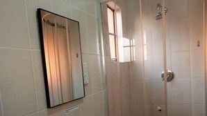 Ein Badezimmer mit Duschkabine, Waschbecken und Spiegel.
