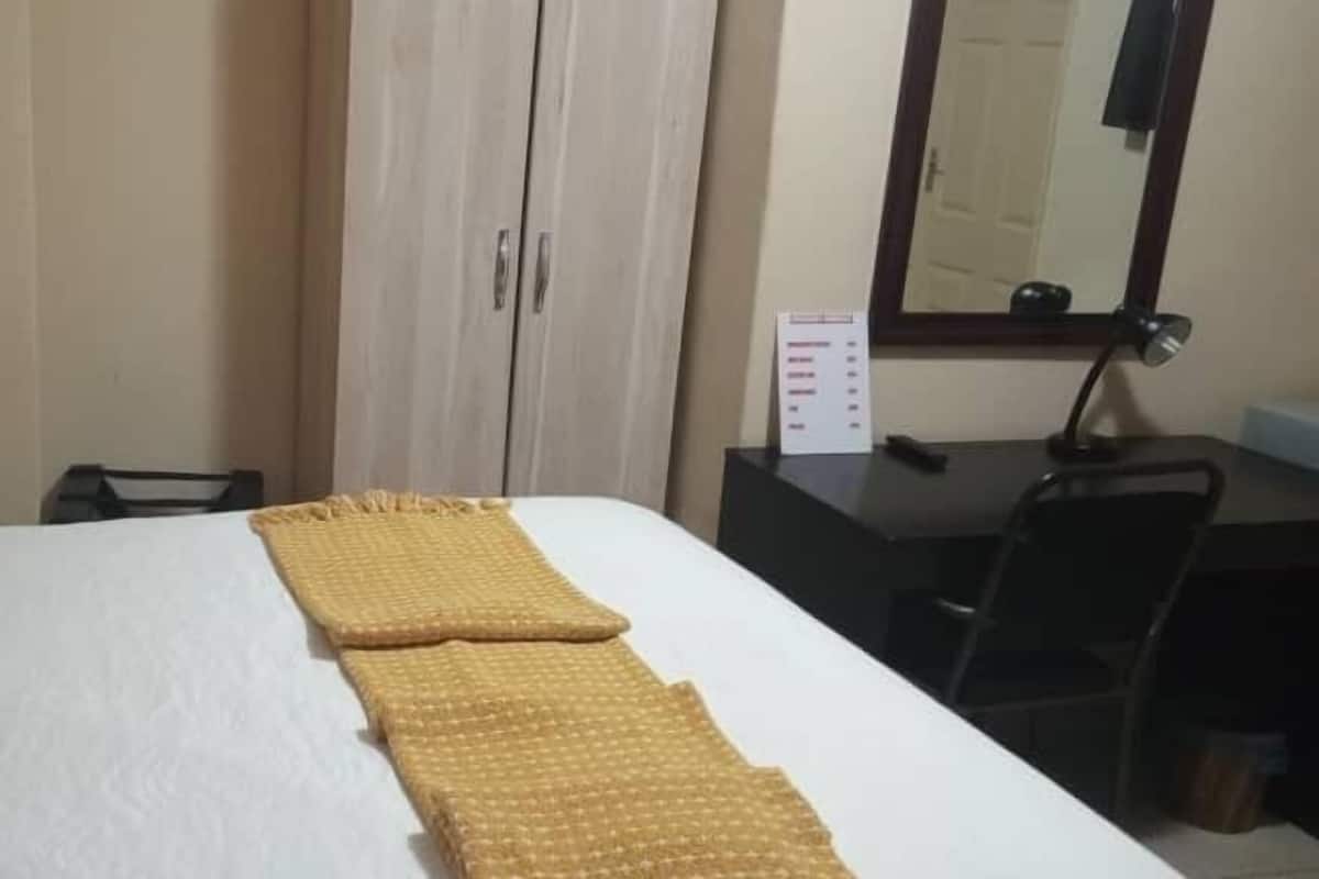 Una habitación de hotel con una cama, un escritorio y un espejo.