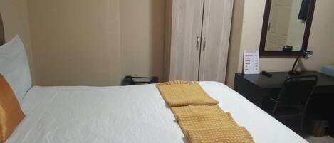 Una habitación de hotel con una cama, un escritorio y un espejo.