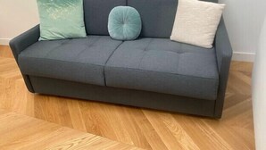 A grey sofa with three cushions in different colors.