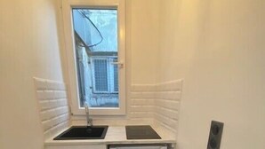 A small kitchen with a window, a sink, and a refrigerator.