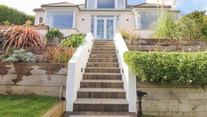 A two-story house with a front staircase leading to a glass door entrance.