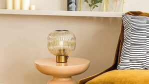 A cozy living room with a round table, a sofa, and a shelf with candles and decorative items.