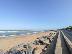 A beach with a concrete walkway and large rocks. - White Rabbit, Cross Lane (Norwich)