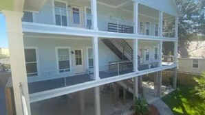 A two-story building with a balcony on the upper floor and a staircase leading to the second floor. - Unit B (Moss Point)