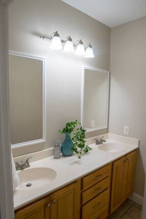 A bathroom with two sinks, a mirror, and a light fixture above the mirrors. - Unit B (Moss Point)