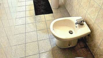 Un baño con ducha, dos lavamanos y un bidé.