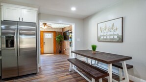 Eine moderne Küche mit Edelstahlgeräten, einem Holztisch und einer Ziegelwand im Hintergrund.